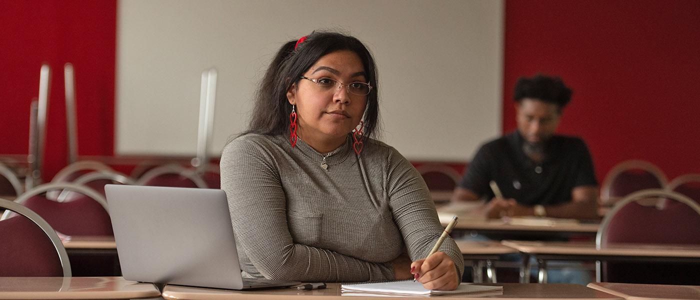 Student sitting at her desk writing on a notebook during class